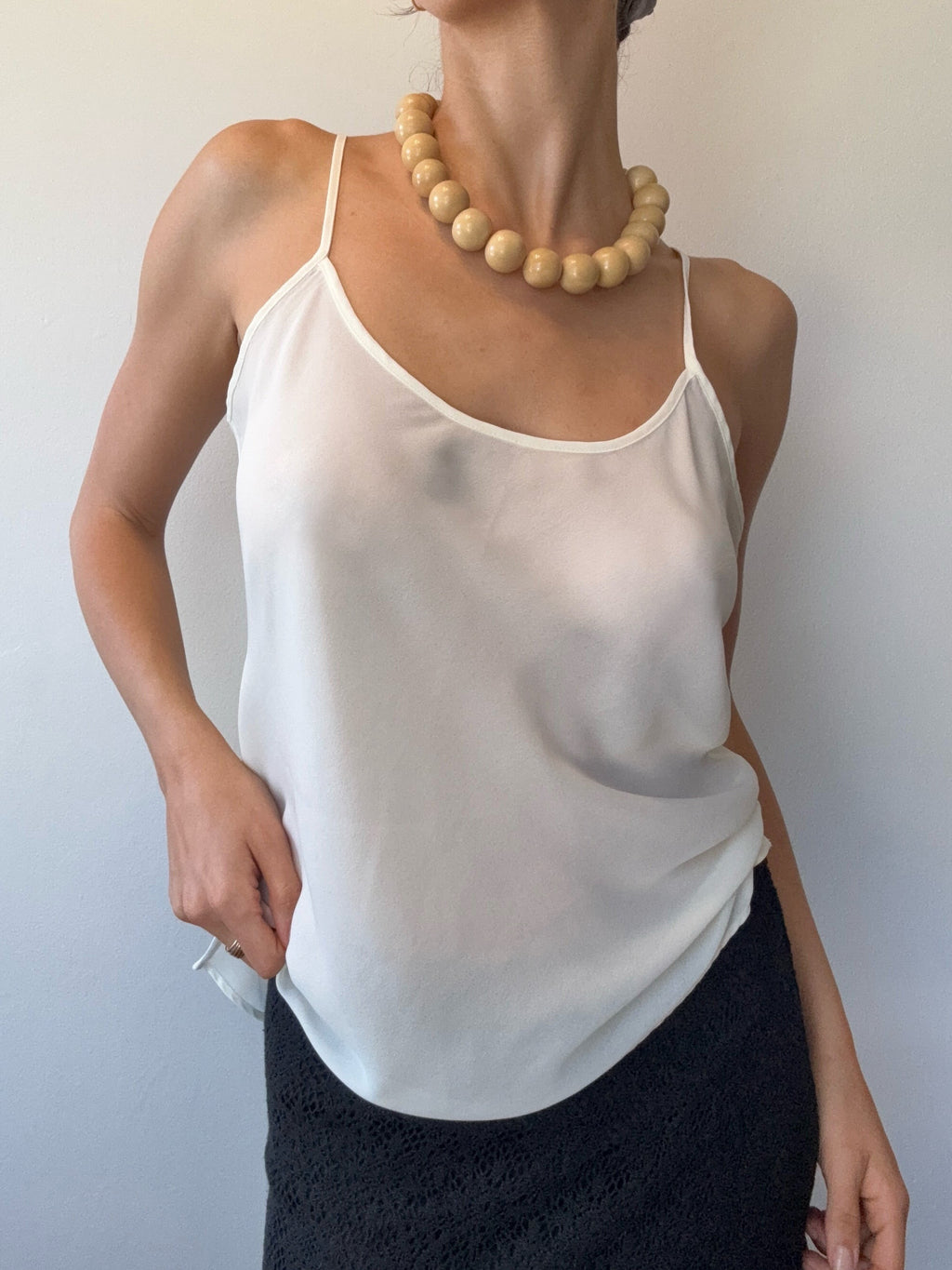 Person wearing a white dress with thin straps on a plain background