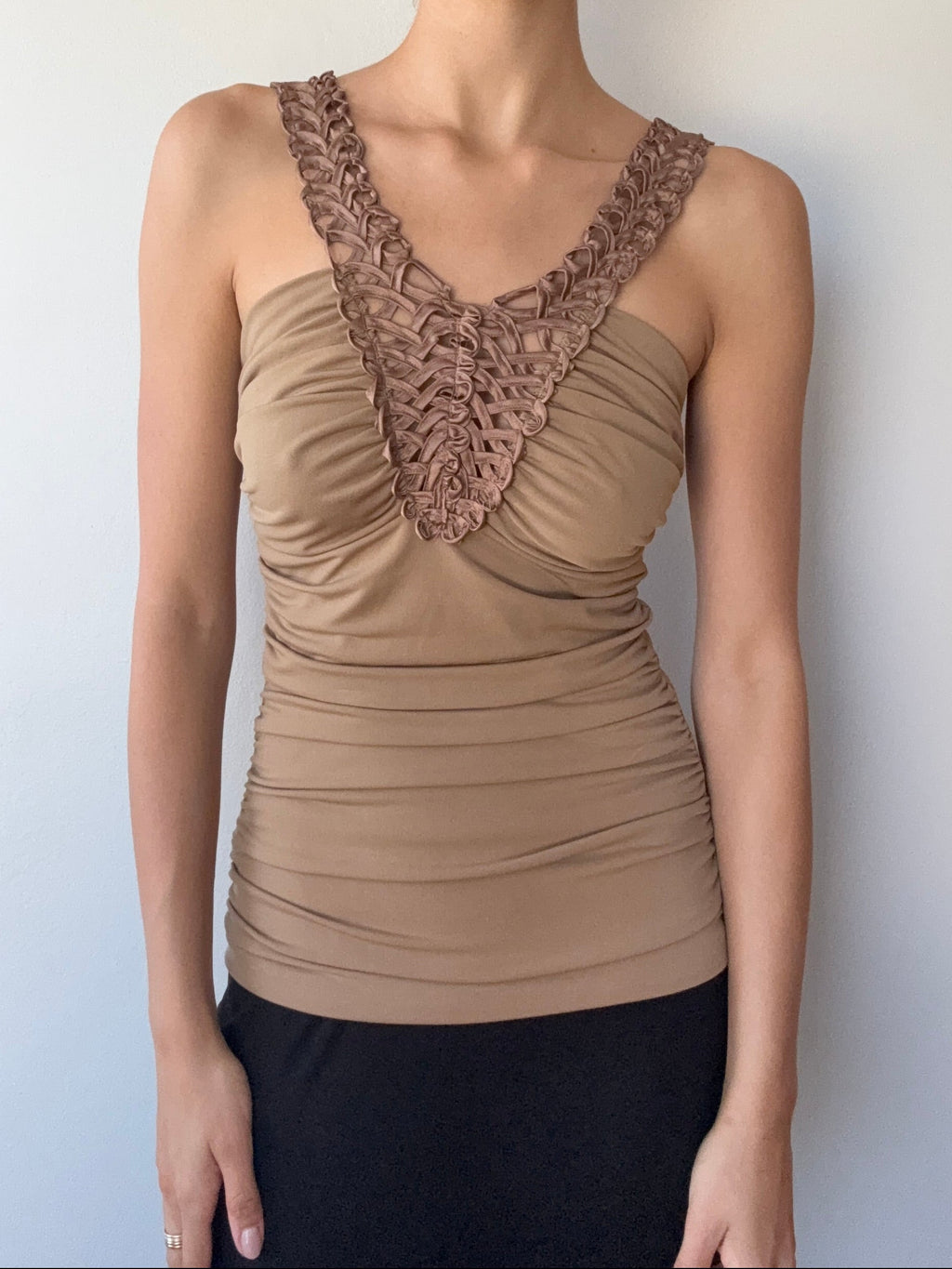 Woman wearing a beige top with lace details on a plain background