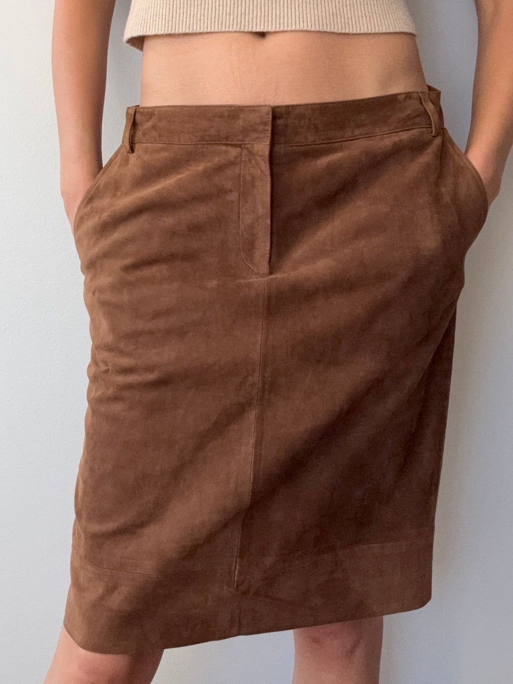 Person wearing a beige sweater and brown pants lying on a white floor.