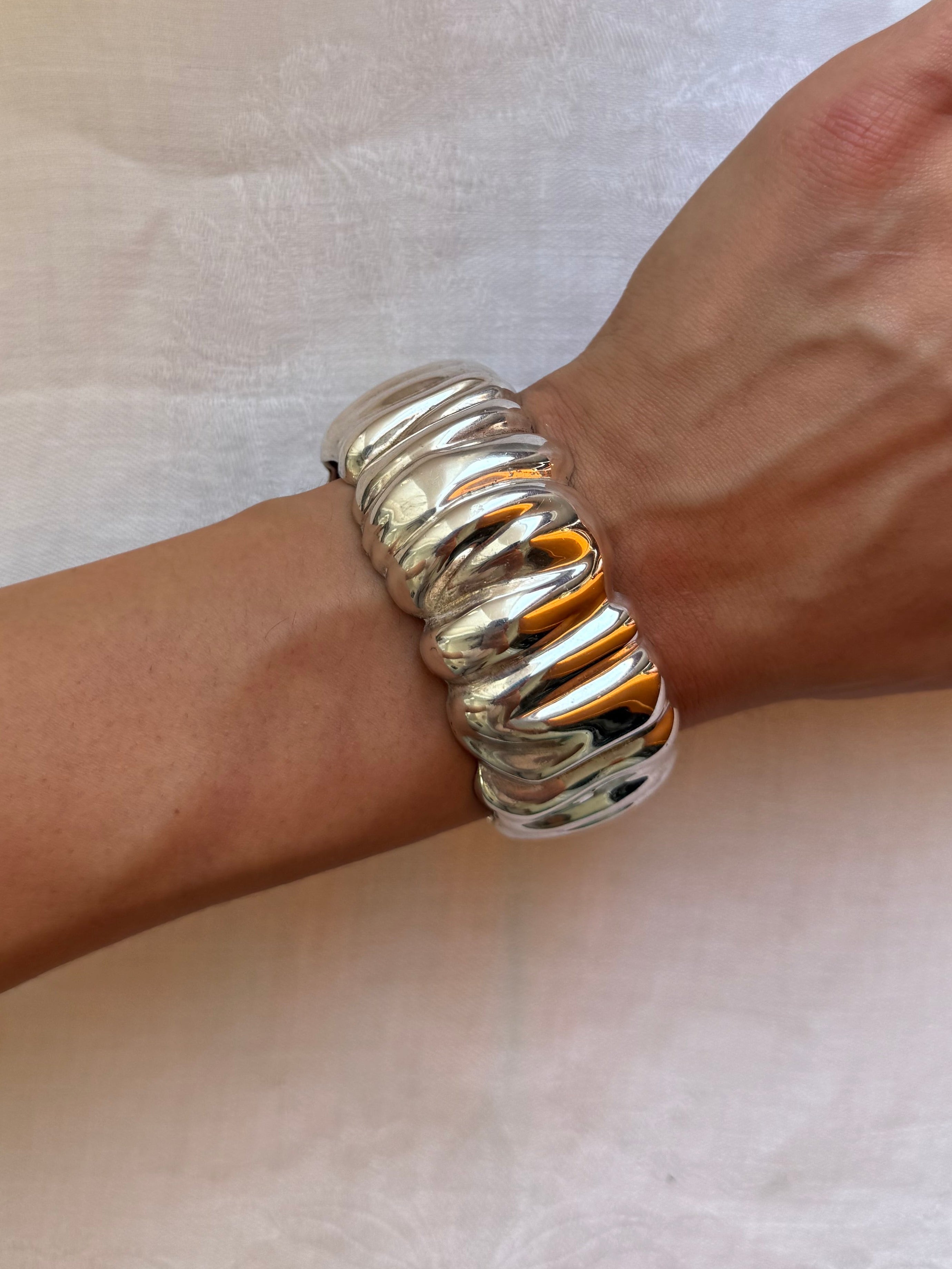 Silver bracelet on a wrist against a white background