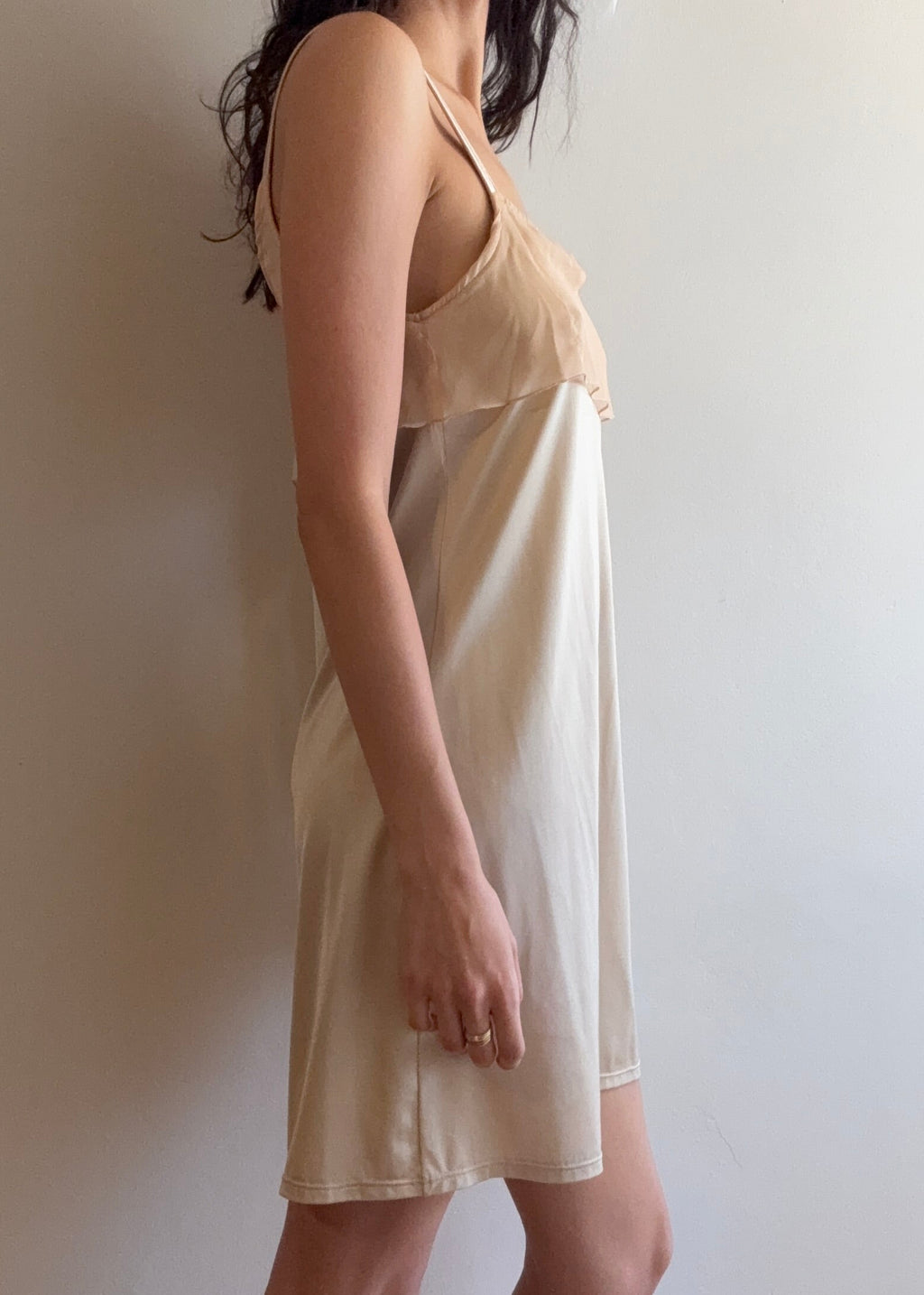 Woman wearing a beige nightgown against a plain background