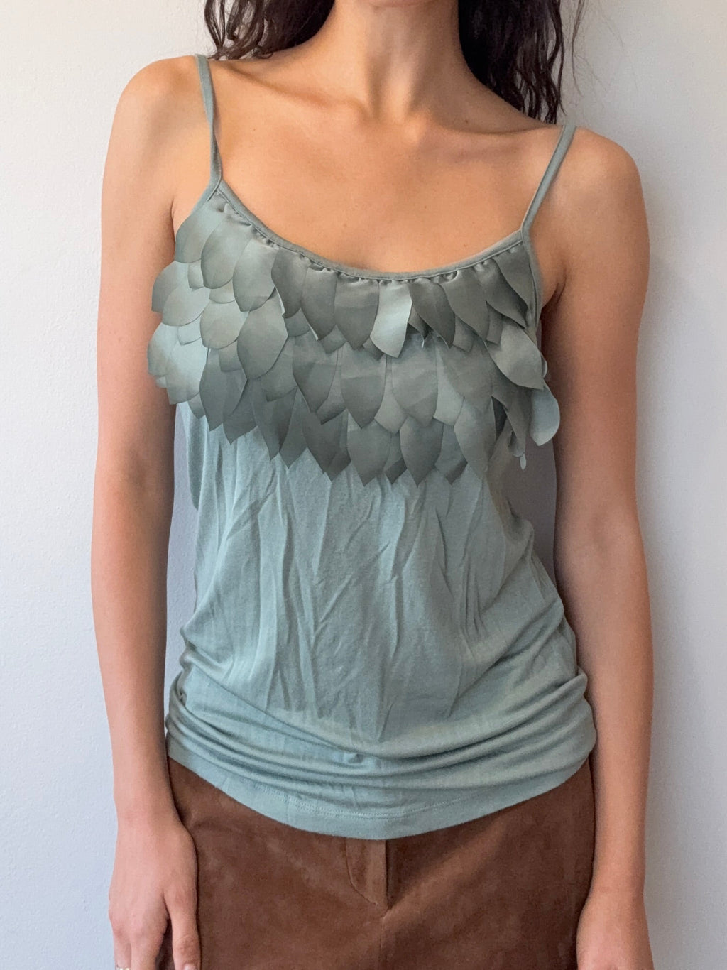 Woman wearing a light blue top with ruffled details and a brown skirt on a plain background