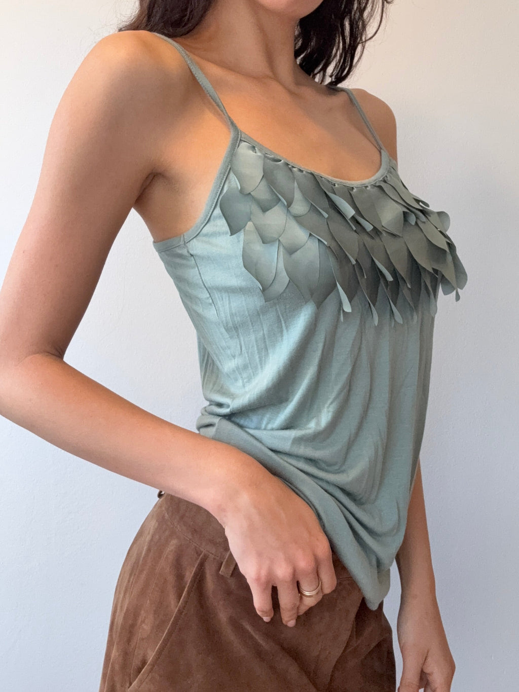 Woman wearing a light green dress with floral patterns on a plain background