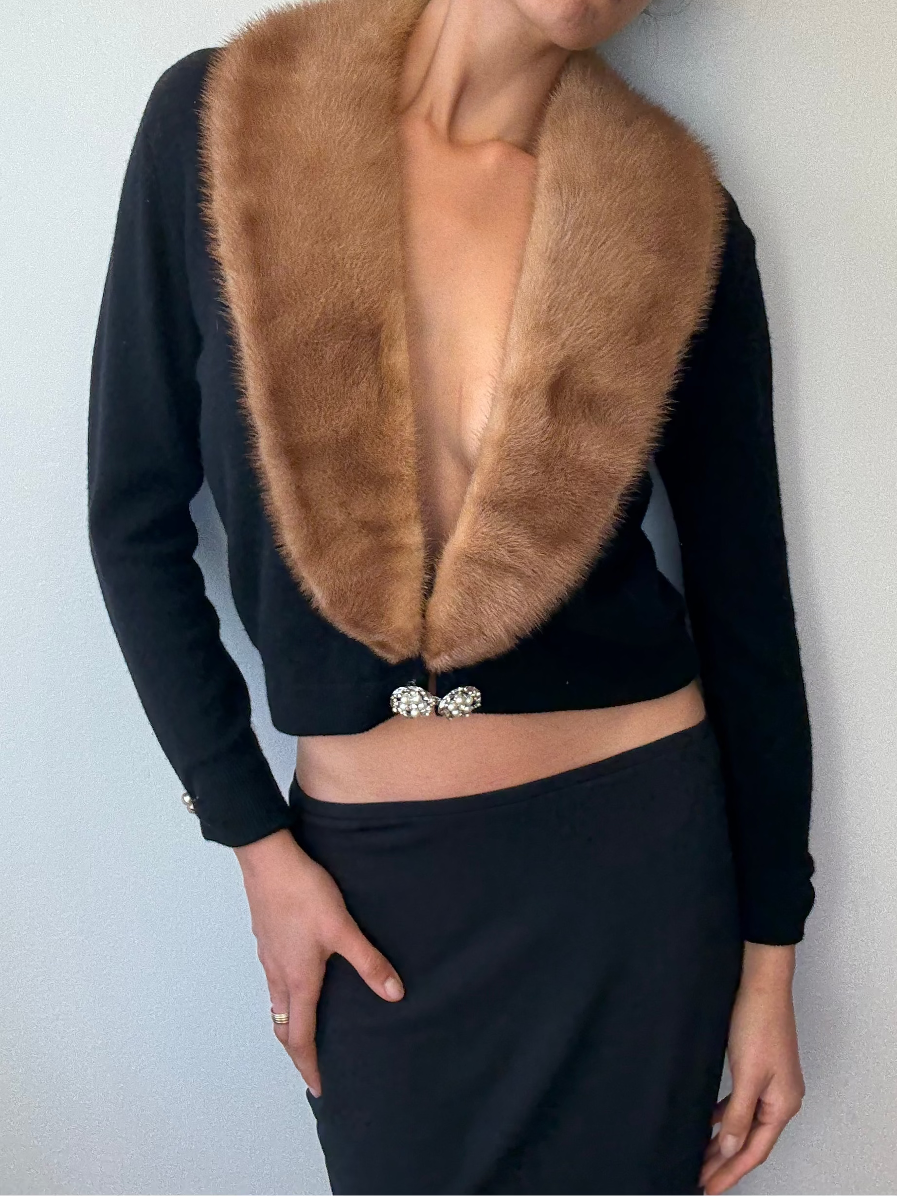 Woman wearing a black top with a fur collar against a plain background