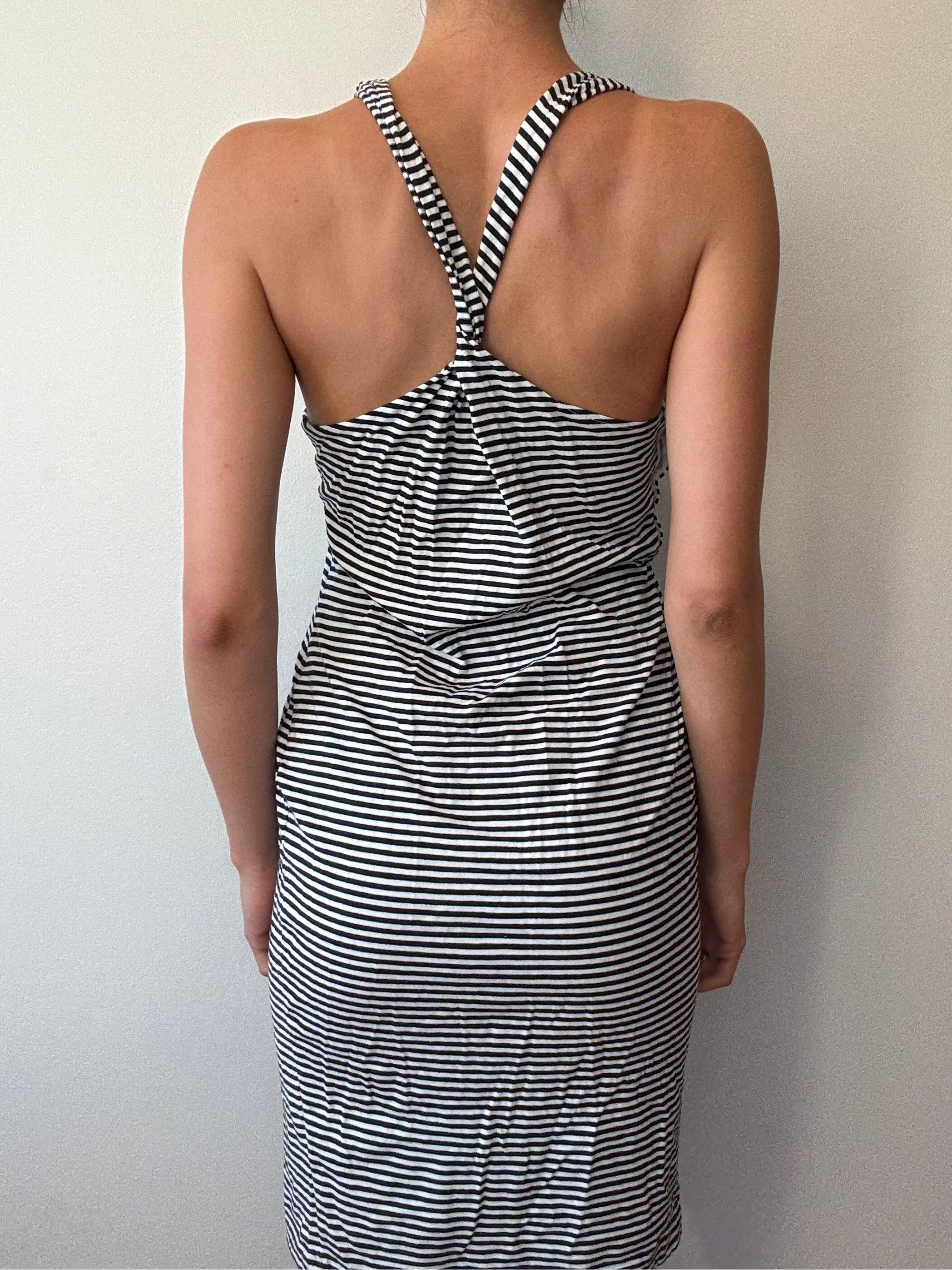 Person wearing a black and white striped dress against a plain background