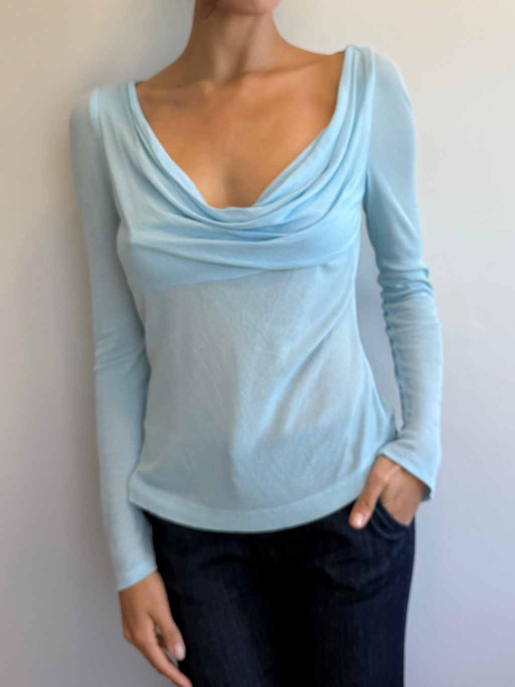 Woman wearing a light blue long-sleeve top against a plain background