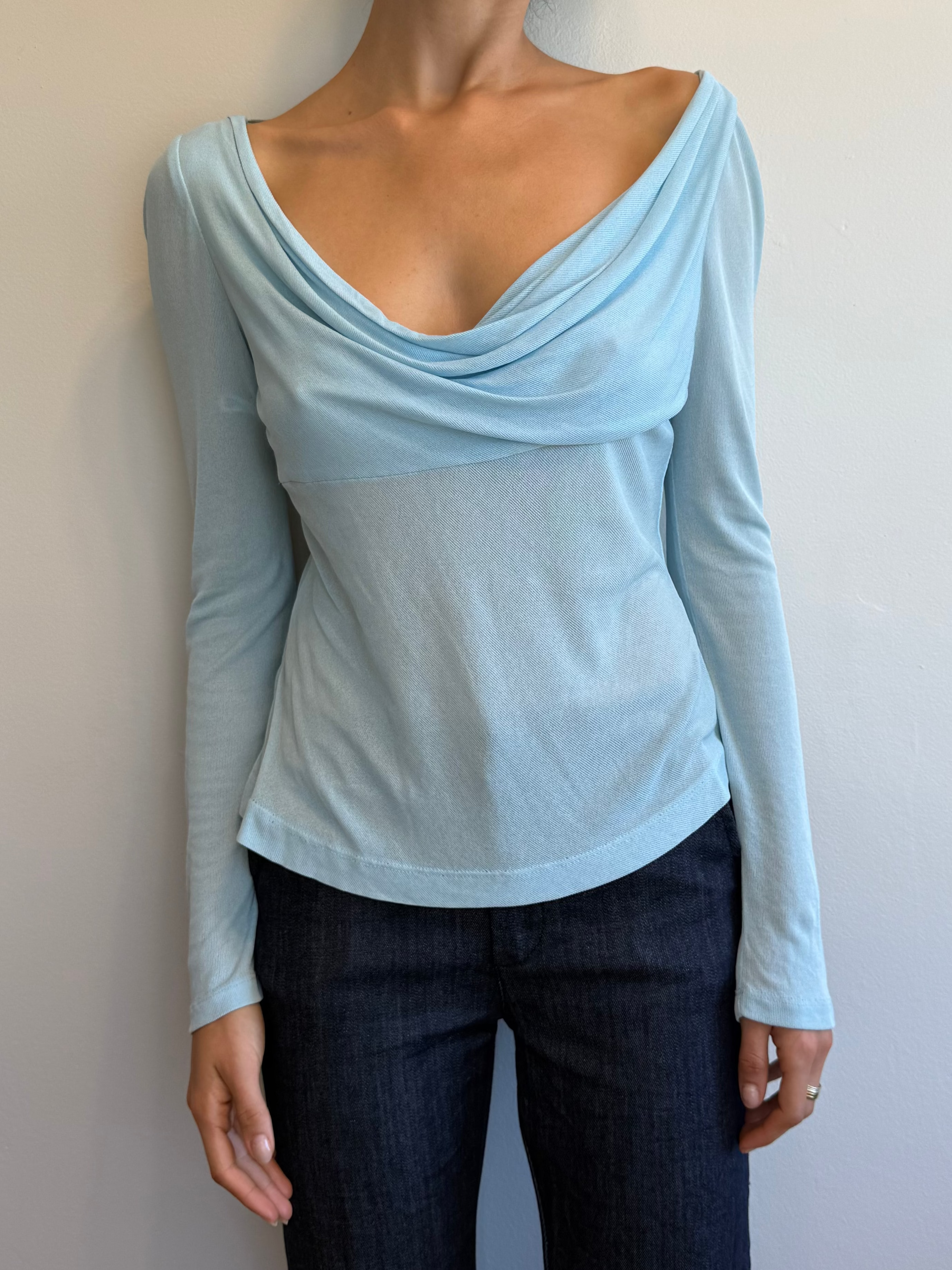 Woman wearing a light blue long-sleeve top against a plain background