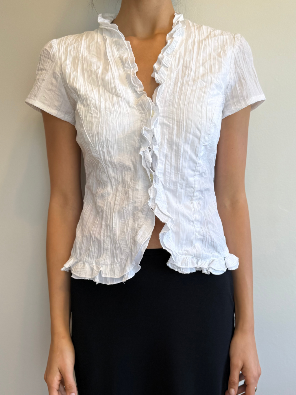 White ruffled blouse worn by a person against a neutral background