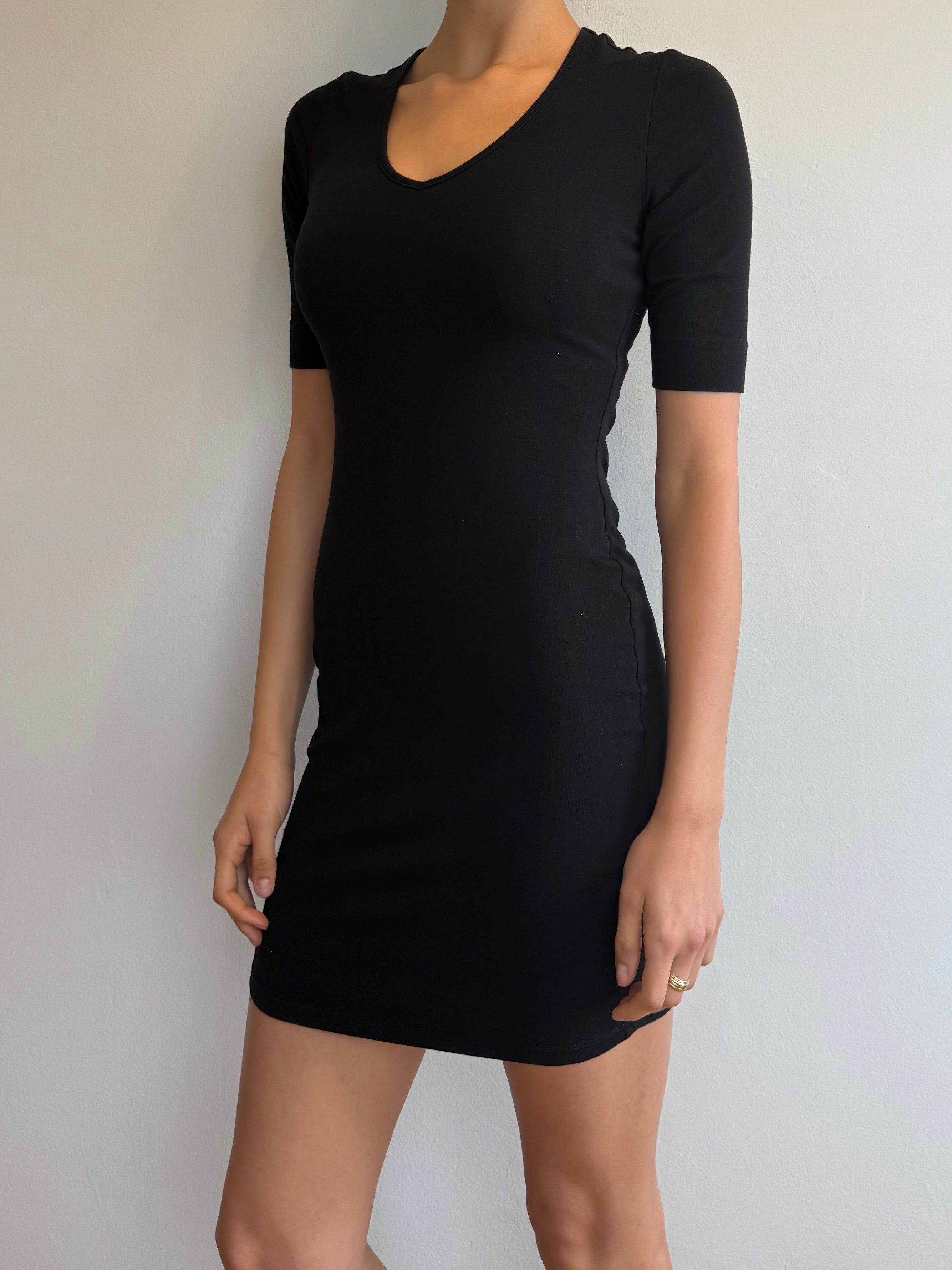 Person wearing a black dress against a plain background