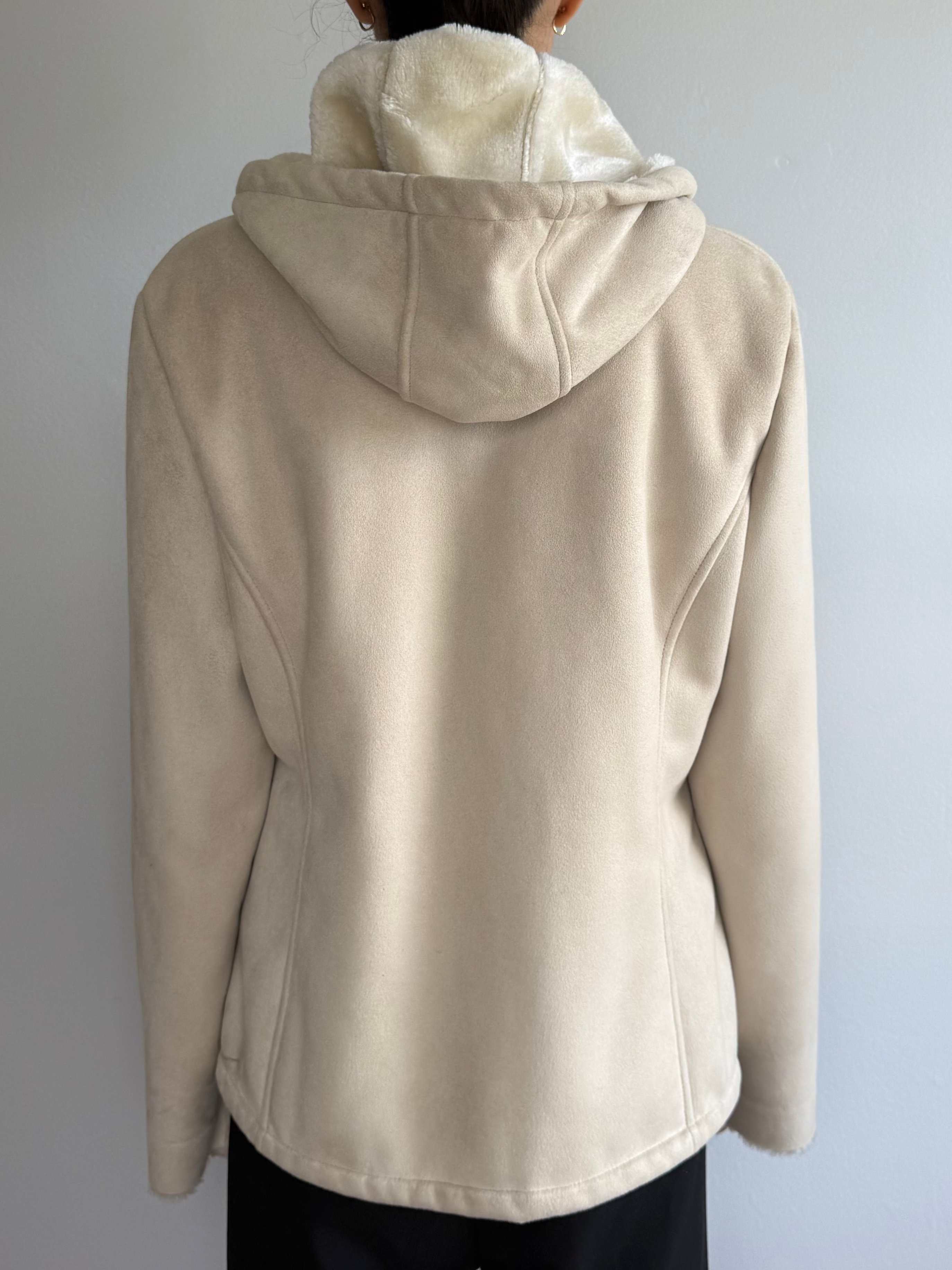 Person wearing a beige hooded jacket against a plain background