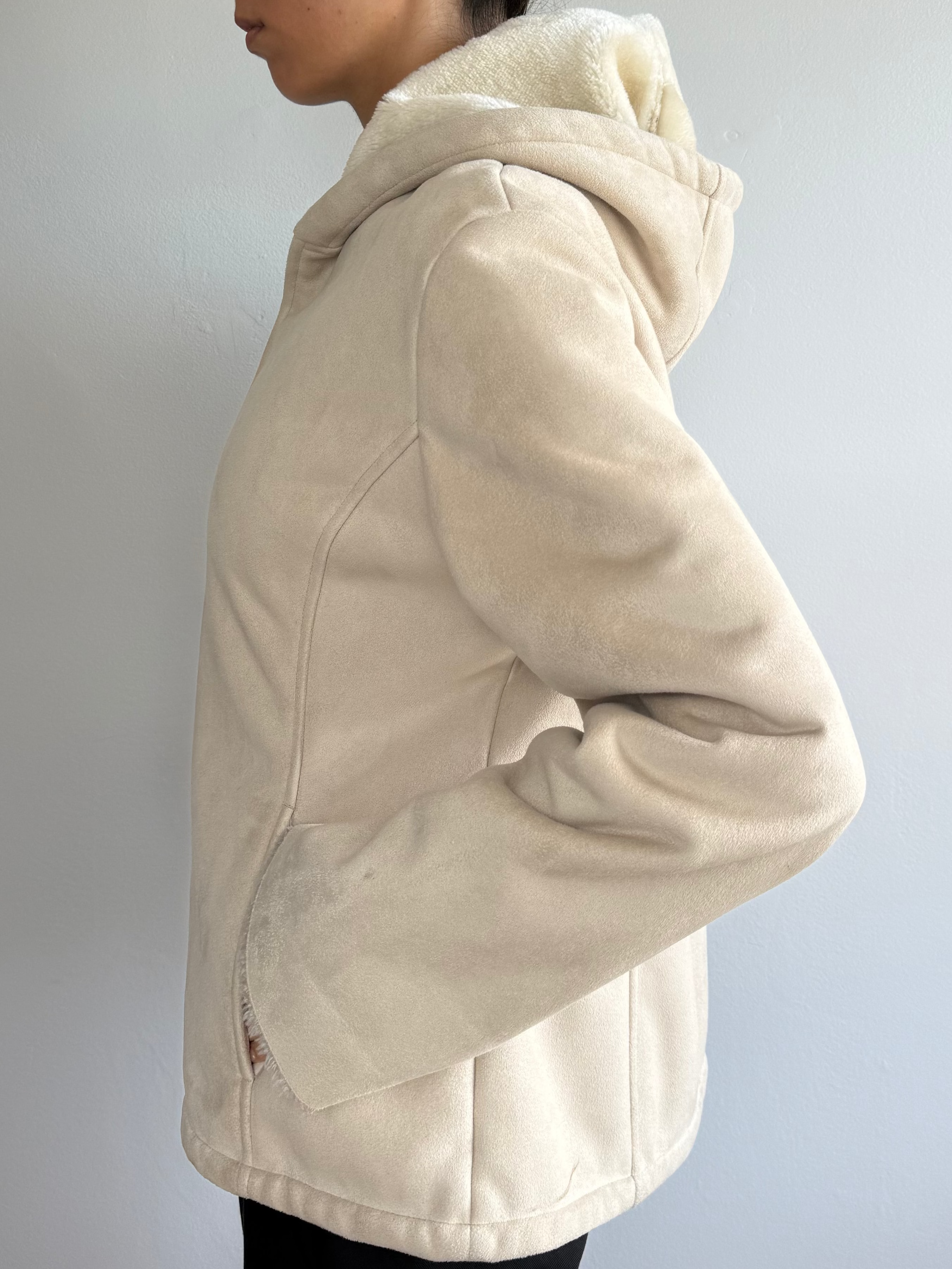 Person wearing a beige jacket against a plain background