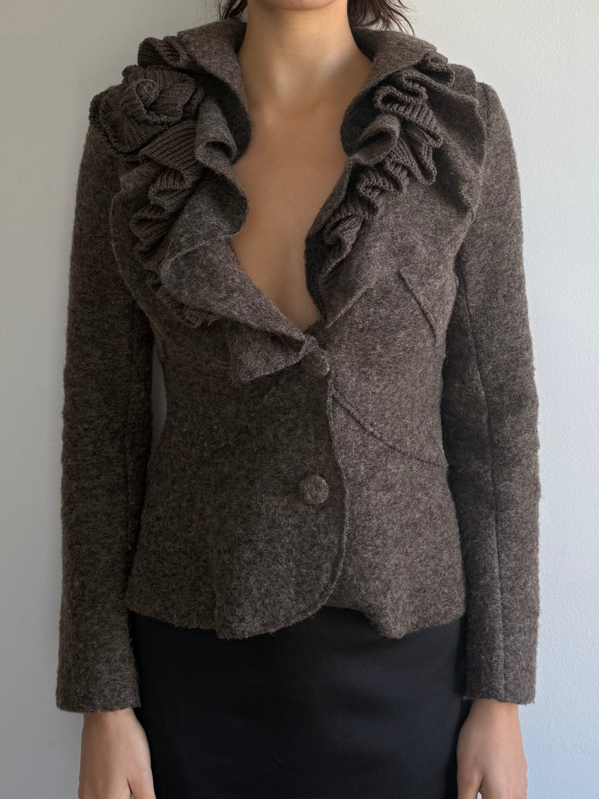 Woman wearing a brown textured jacket against a plain background