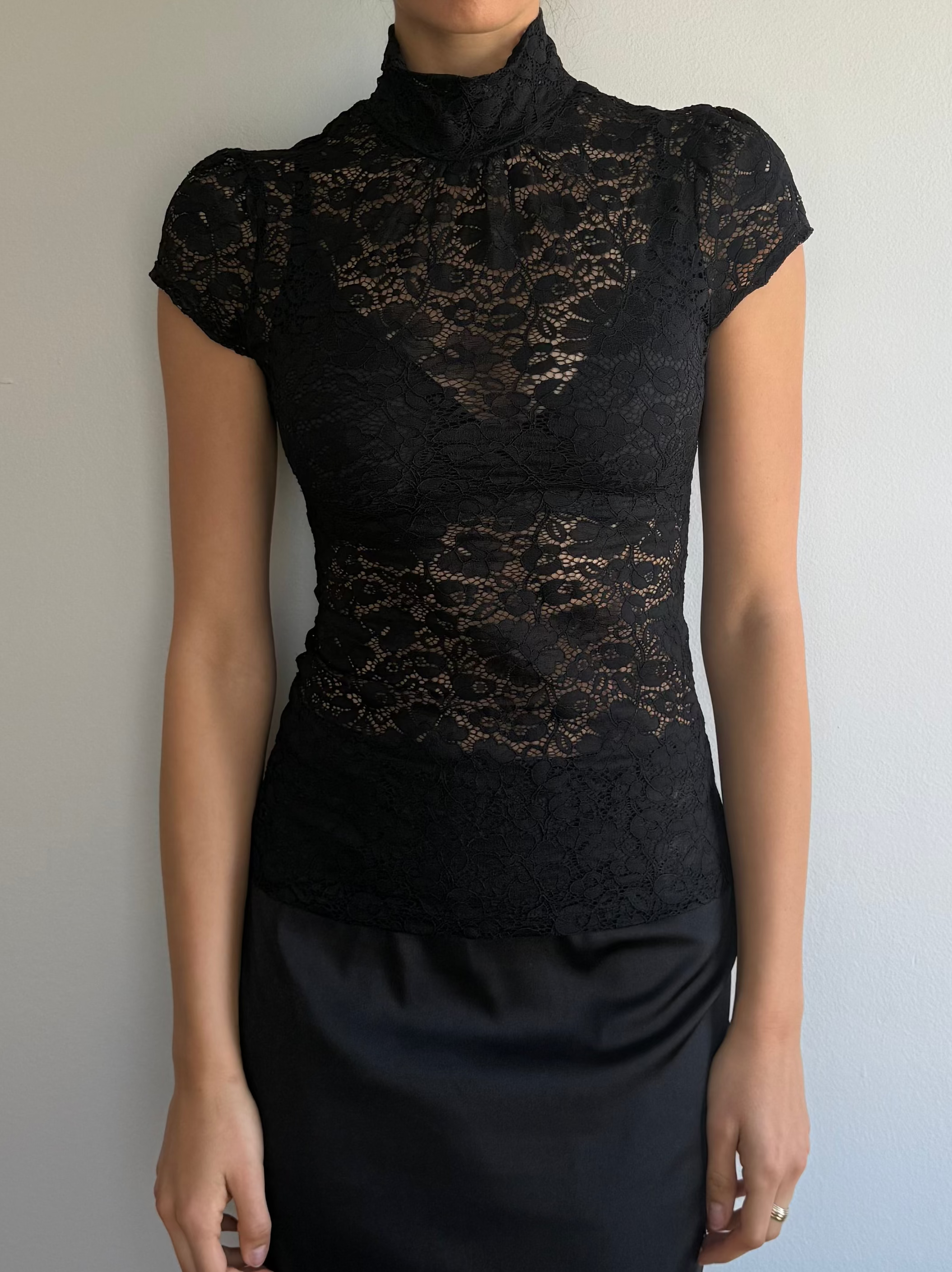 Woman wearing a black lace dress against a plain background
