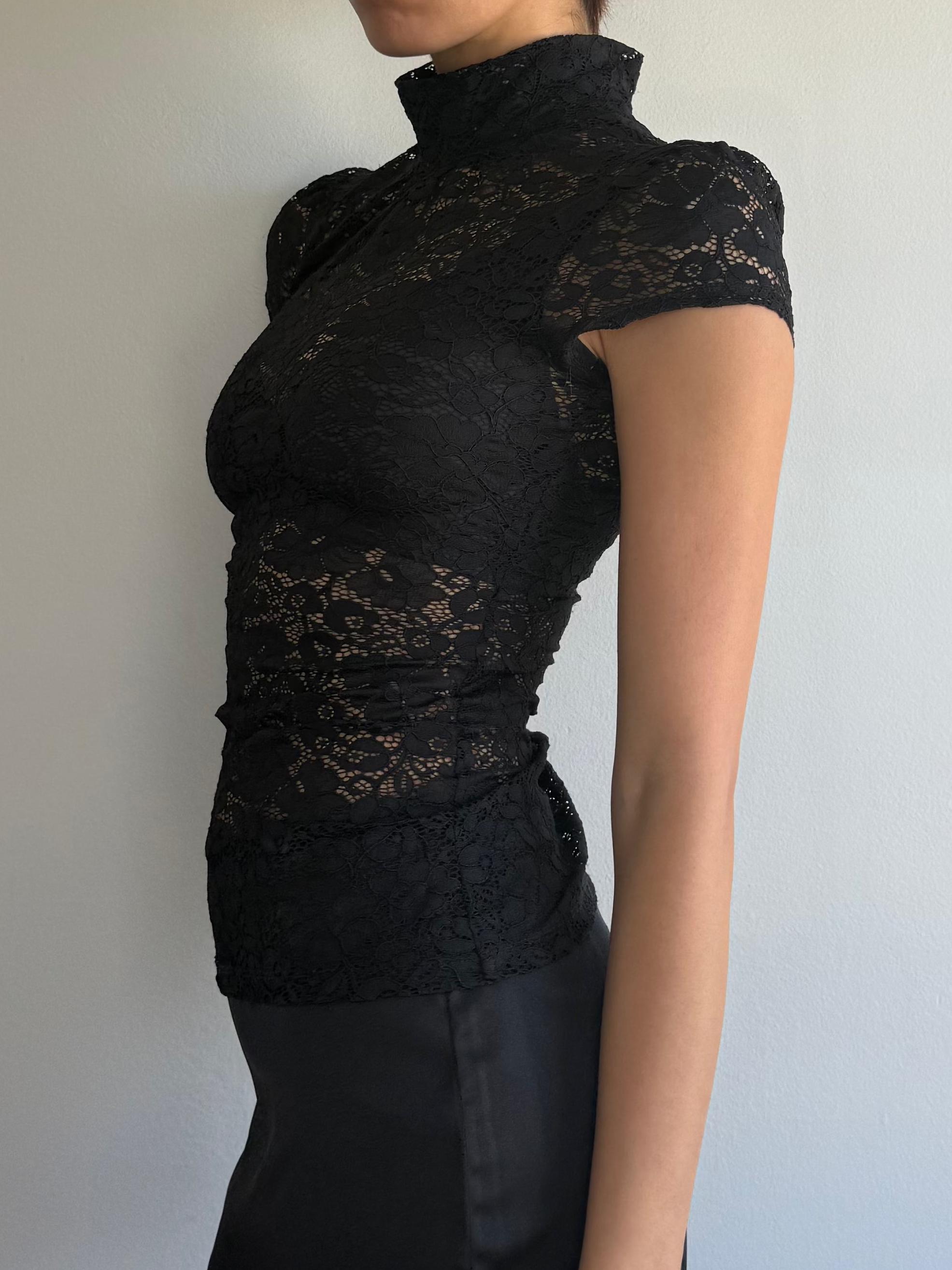 Woman wearing a black lace top and black skirt against a plain background