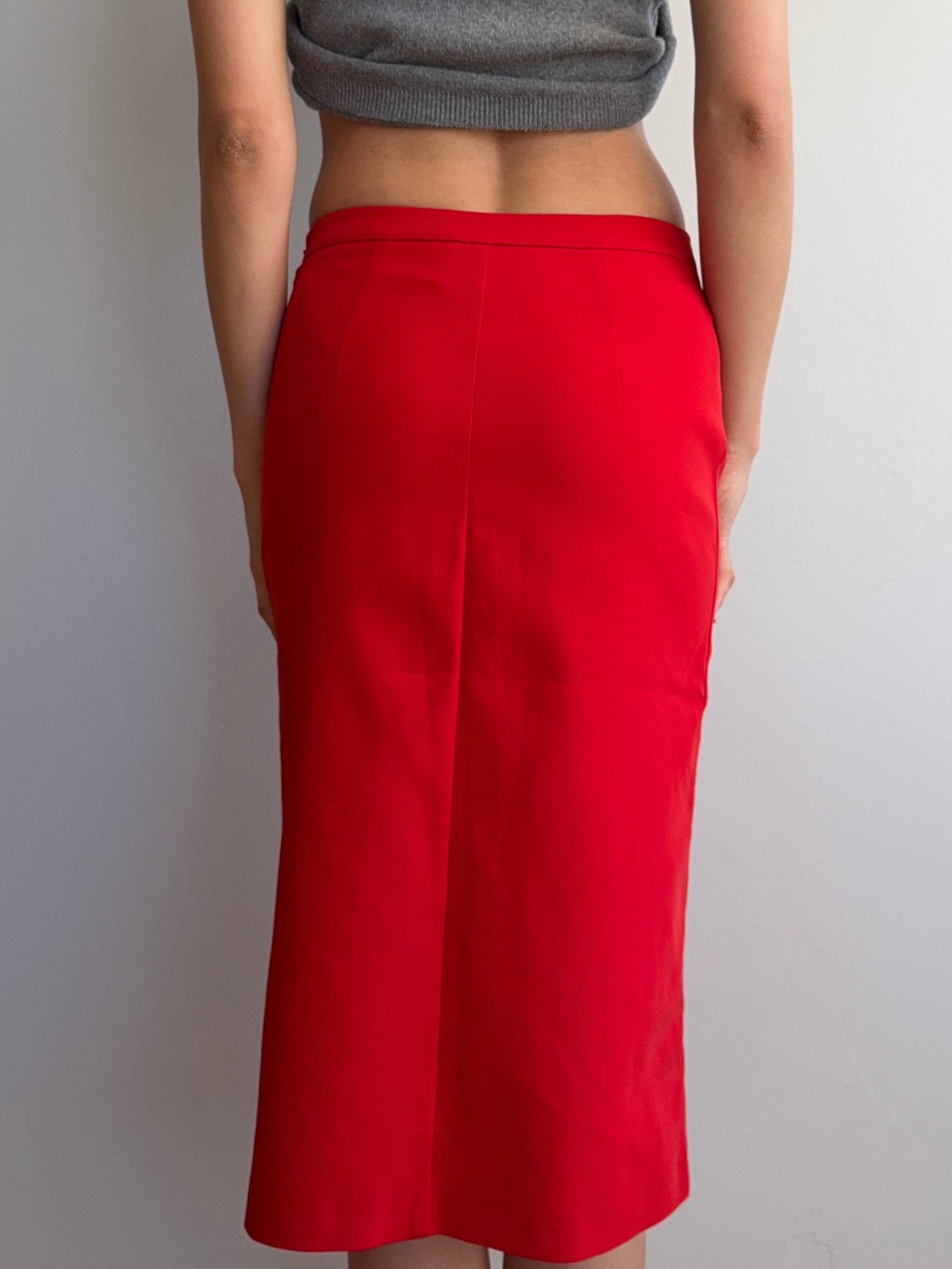 Person wearing a red skirt and gray top against a plain background
